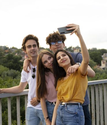 group-four-friends-spending-time-together-outdoors-taking-selfie